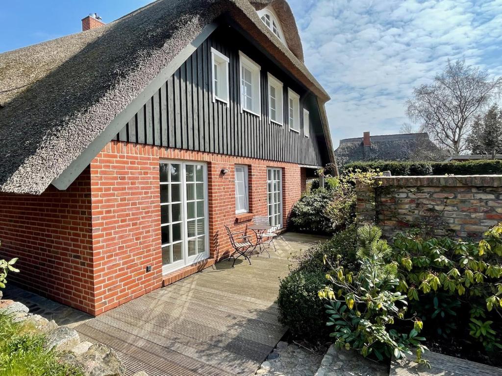 une maison avec un toit de chaume et une terrasse dans l'établissement Ferienwohnung am Apfelgarten, à Ahrenshoop