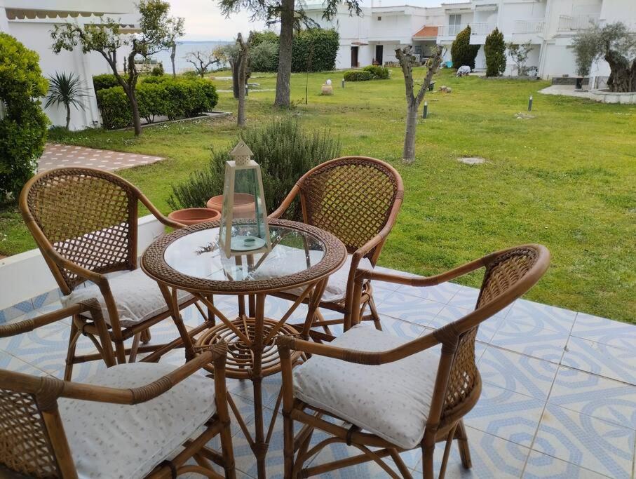 uma mesa de vidro com 4 cadeiras num pátio em 7 Seas House em Kalivia Poligirou