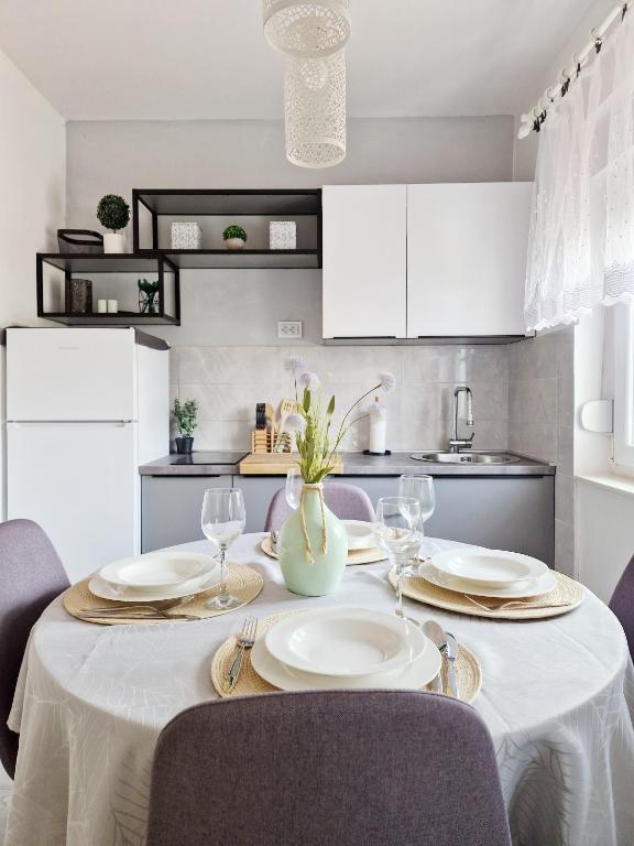 a dining room table with a white table cloth and glasses at Apartman Marijana in Pakoštane