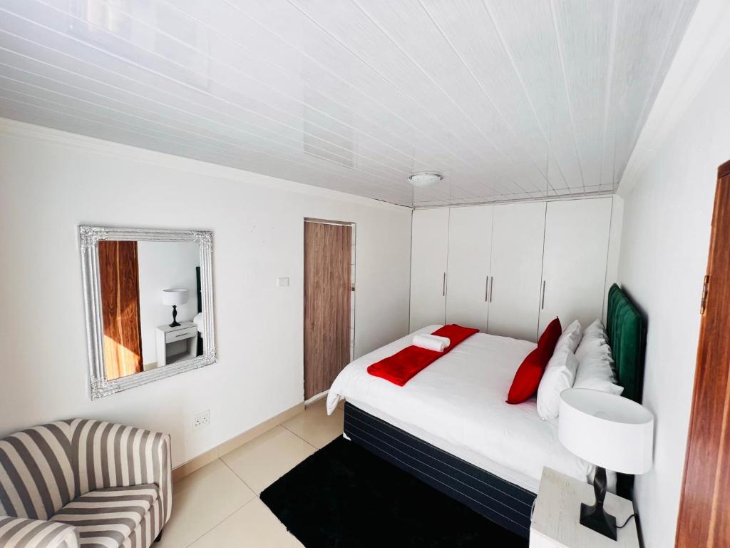 - une chambre blanche avec un lit et une chaise dans l'établissement Safi 1 bedroom Suite 9, à East London