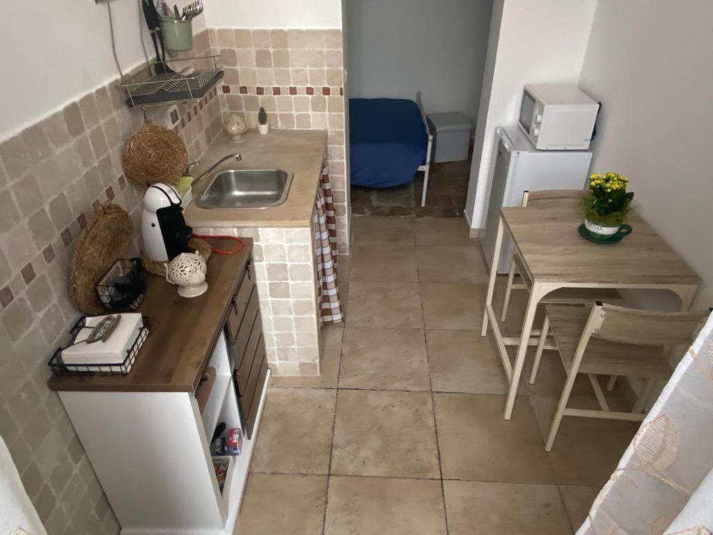 Una pequeña cocina con un fregadero y una mesa. en Dimora Serena, en Ostuni