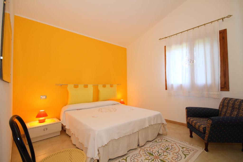 sypialnia z żółtymi ścianami, łóżkiem i krzesłem w obiekcie Casa sulla collina - Sant'Antioco w mieście SantʼAntìoco