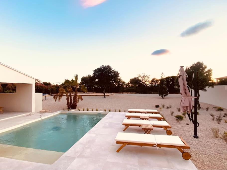 a group of lounge chairs next to a swimming pool at Villa moderne entre centre ville et nature in Nîmes