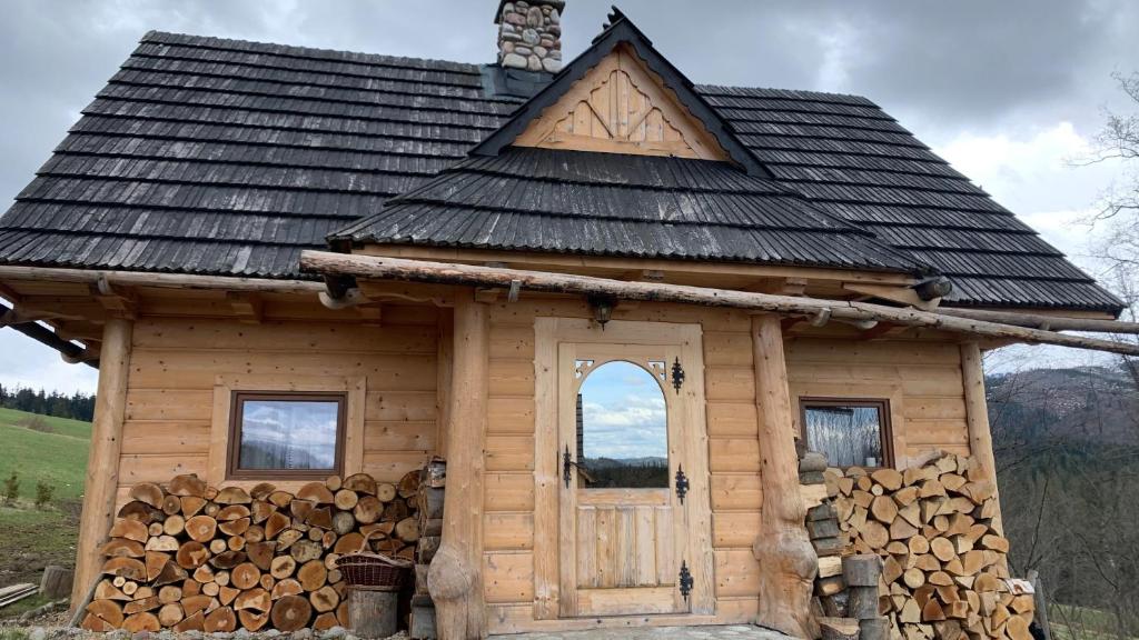 een kleine houten hut met een stapel houtblokken bij Domki na wzgórzu 2 in Ciche Małe