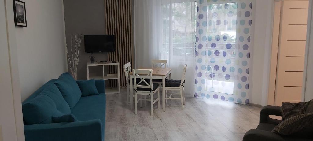 sala de estar con sofá azul y mesa en Apartament 4YOU en Pobierowo