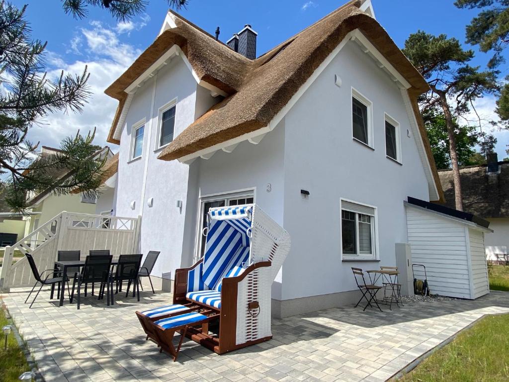 a house with a thatched roof and chairs on a patio at Min Droom Usedom in Zirchow