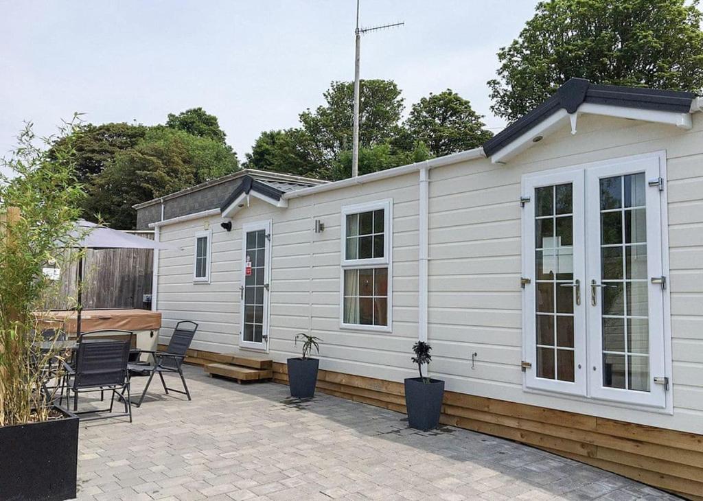 a white house with chairs and a patio at Stream Valley Holiday Park in Penzance