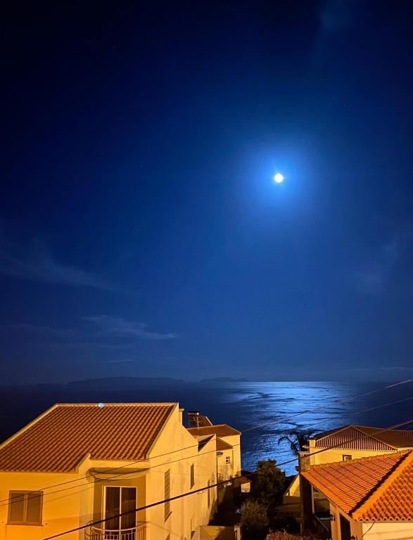 a full moon over the ocean and houses at night at Villa Madeira island in Caniço
