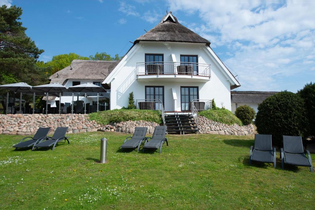 a large white house with chairs in the yard at Pension Ari am See in Ostseebad Sellin