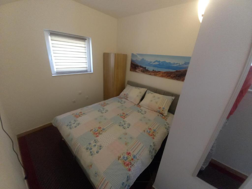 a small bedroom with a bed and a window at Studio Apartman Šutić in Kastel Novi