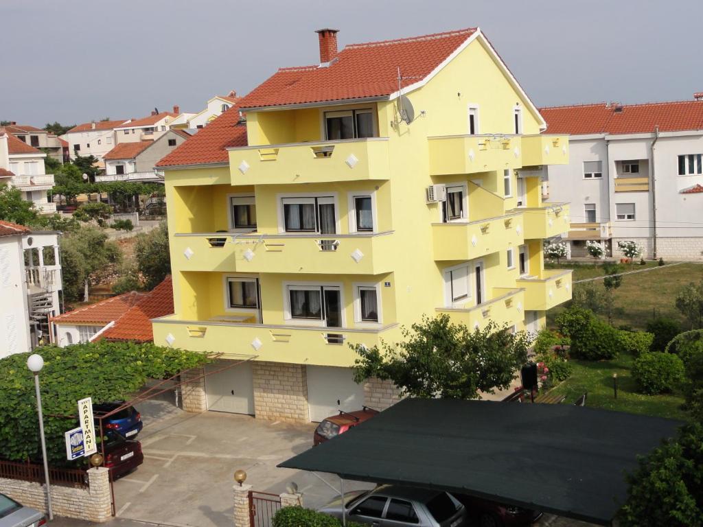a yellow building with a red roof at Apartments Sestan in Zadar