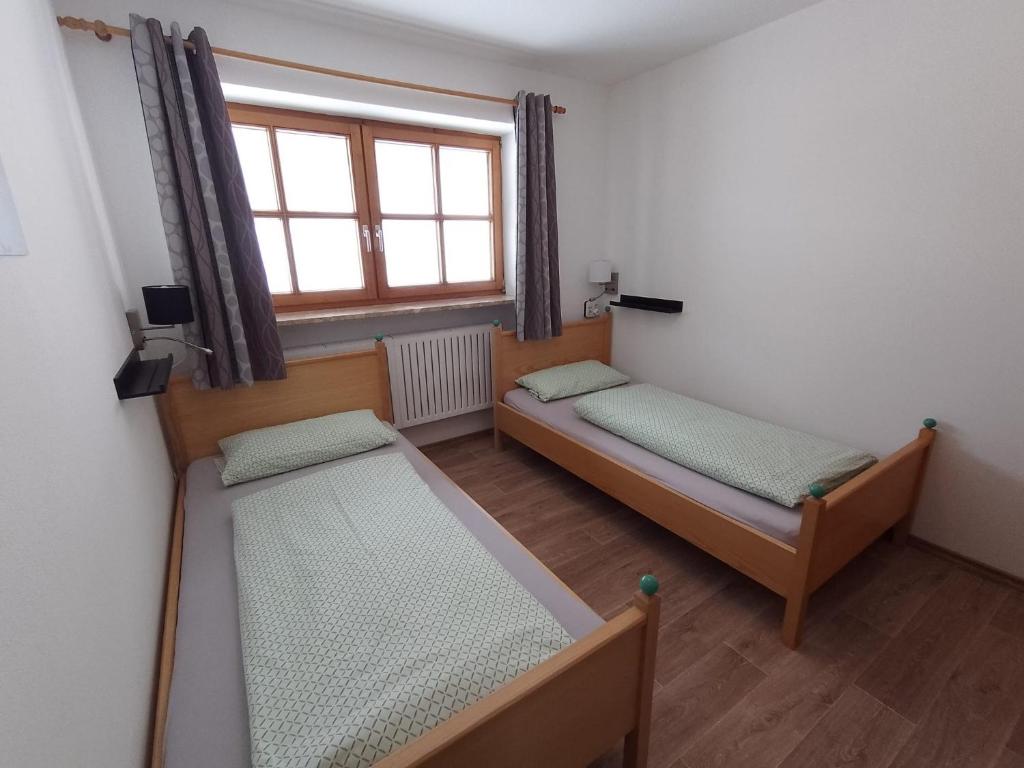 a small room with two beds and a window at Bio Berghof Langerlehen in Berchtesgaden