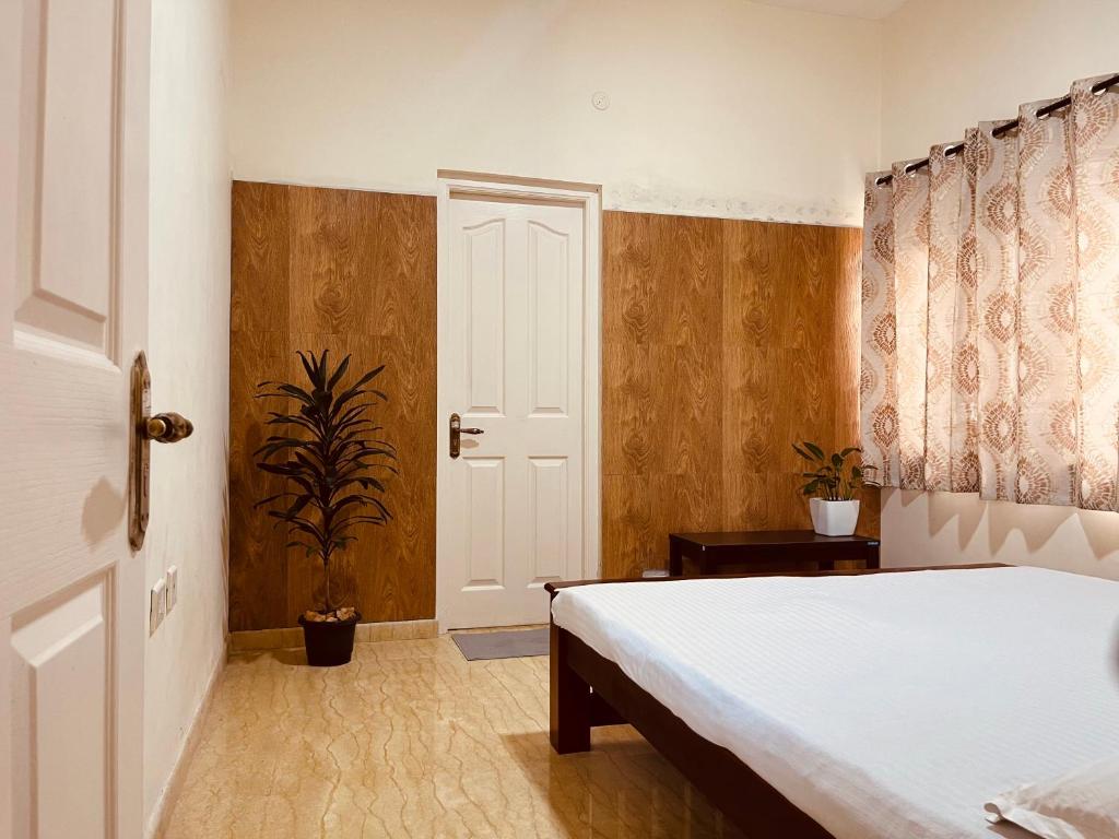 1 dormitorio con cama blanca y paredes de madera en Nilgiri Comfort Stay, en Coonoor