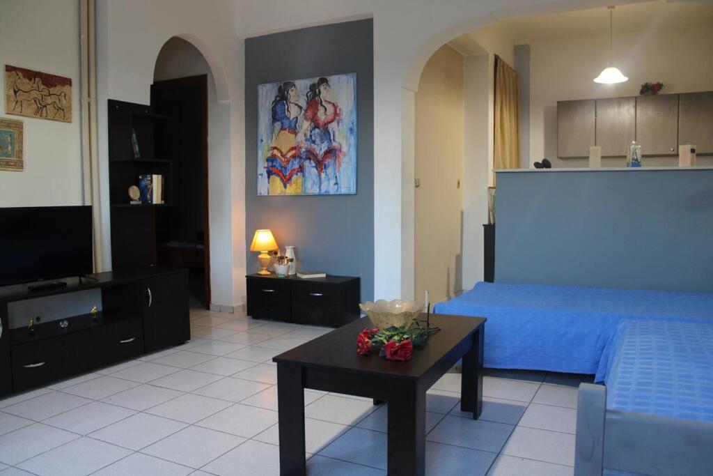 a bedroom with a blue bed and a table with flowers on it at Rodi Apartments 1 in Kamari