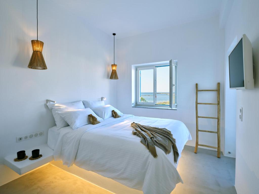 a white bedroom with a white bed with a ladder at CasaZu in Naousa