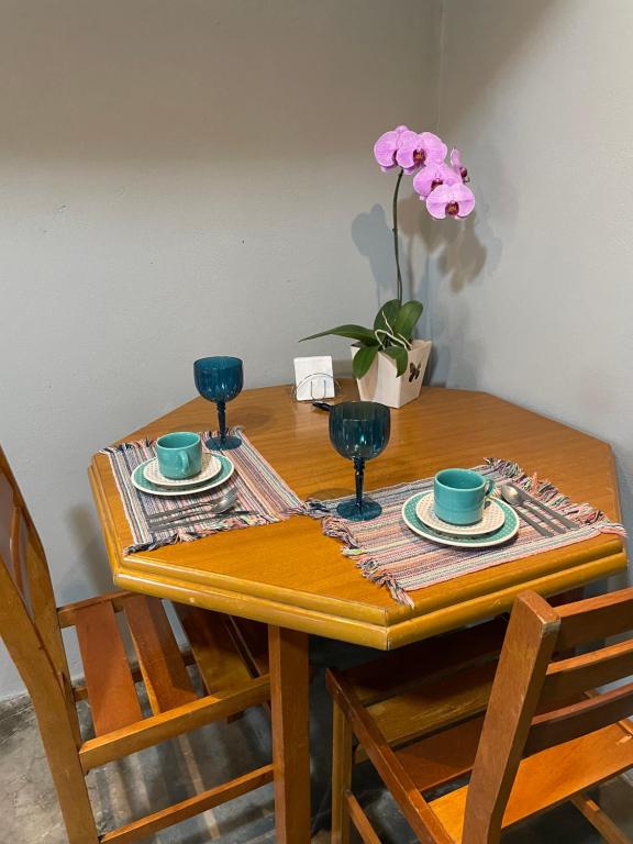 einem Holztisch mit zwei Tassen und einer Vase Blumen in der Unterkunft Casa da Rota in São Roque