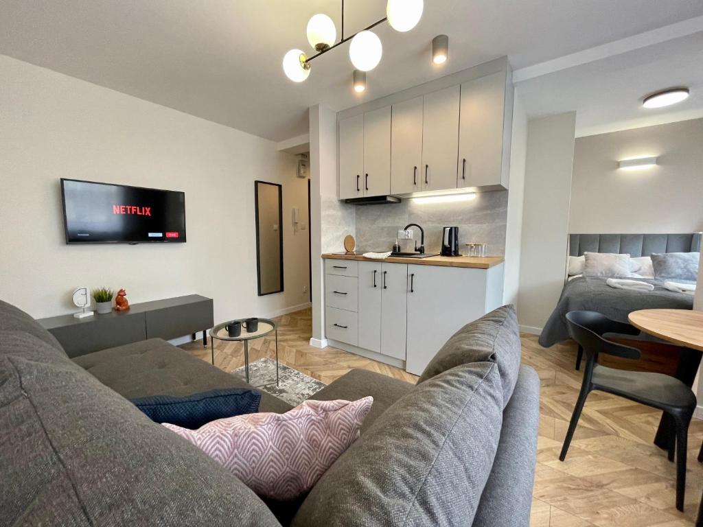 uma sala de estar com um sofá, uma mesa e uma cozinha em Przytulny Apartament niedaleko Radomskiego Centrum Sportu em Radom