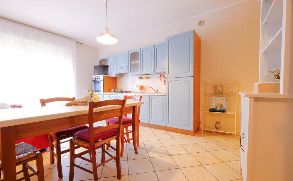uma cozinha com armários brancos e uma mesa e cadeiras em Poseidon 5 - Pineto Vacanza em Pineto