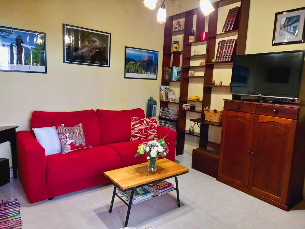 uma sala de estar com um sofá vermelho e uma mesa em La casa de Isabel em Mazo