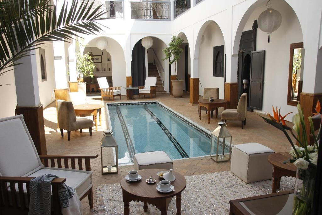 einen Pool in einem Haus mit Stühlen und Tischen in der Unterkunft Riad Utopia Suites And Spa in Marrakesch