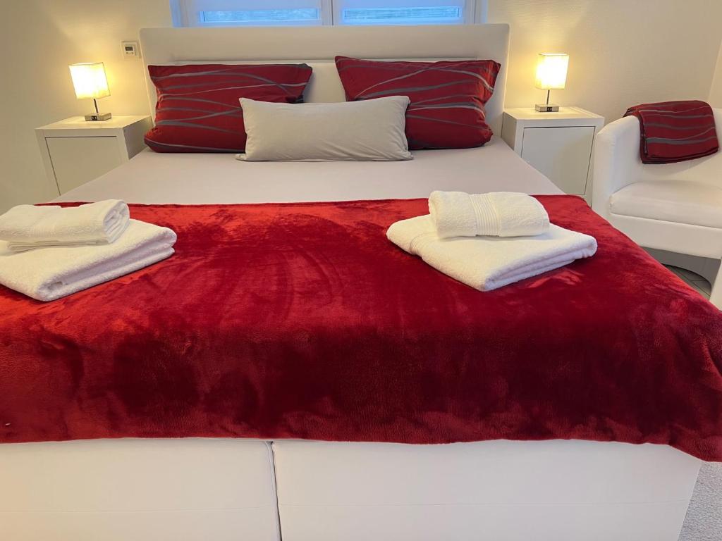 Una cama roja y blanca con dos toallas. en FEWO-Engelgrundweiher en Schmelz
