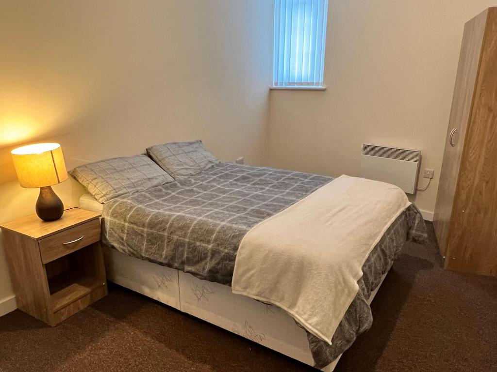 a bedroom with a bed and a lamp on a night stand at Two Bed Town Apartment in Rotherham