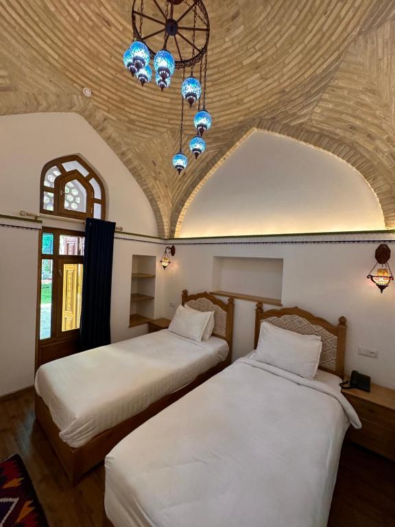 two beds in a room with a ceiling at Marhaba boutique Madrasah 15th-16th century in Bukhara