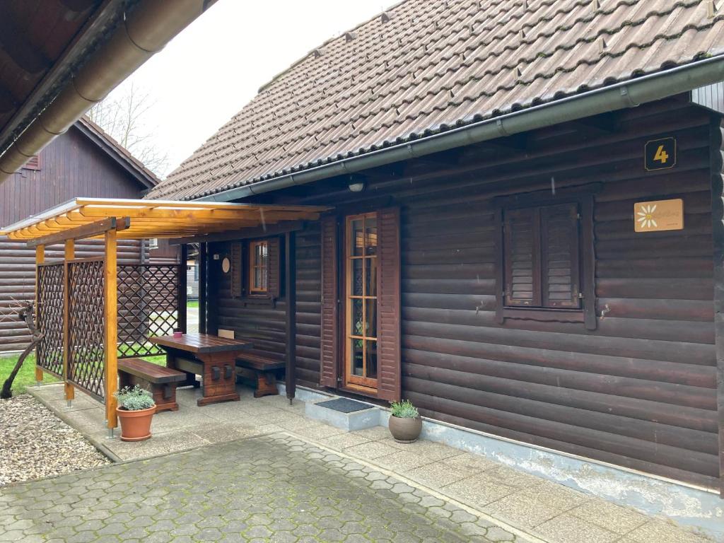 a wooden cabin with a bench and a table at Hiška Marjetica in Podčetrtek