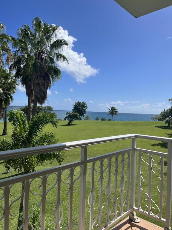 a balcony with a view of the ocean and palm trees at Appartements VUE MER et PARC in Sainte-Luce