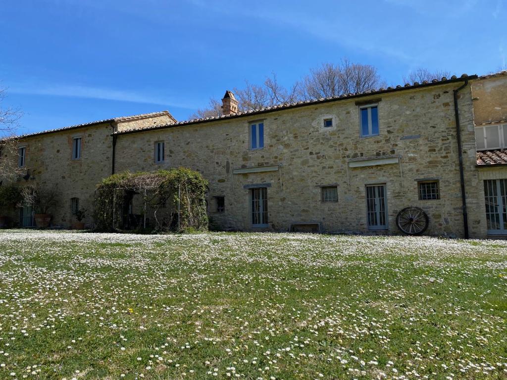 a large stone building with a grass field in front of it at L'ocanda Rancioli in San Casciano dei Bagni