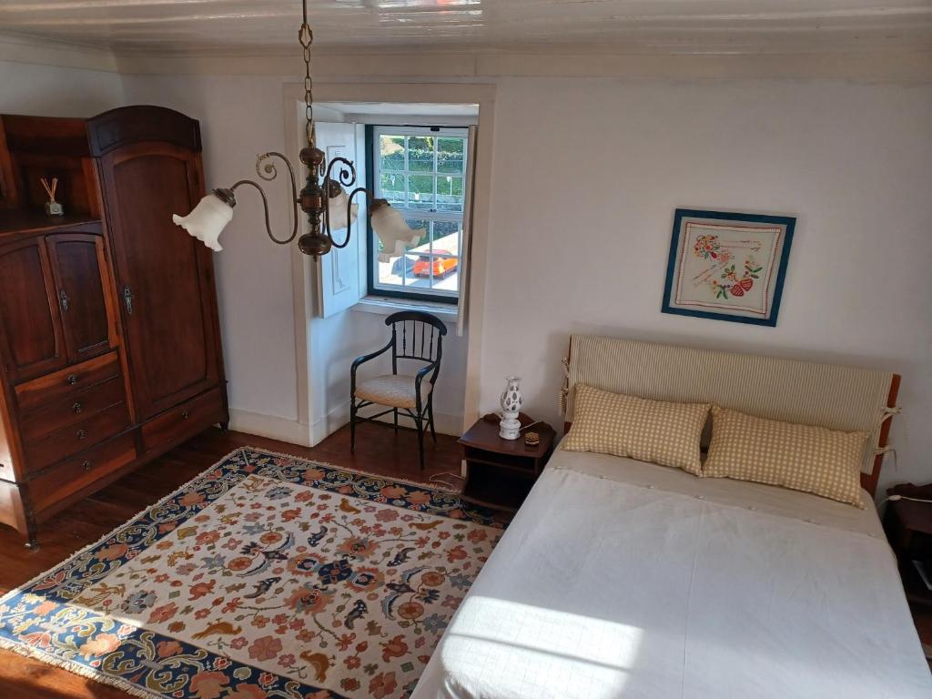 um quarto com uma cama, uma cadeira e uma janela em Casa da Ponte, Coja em Coimbra