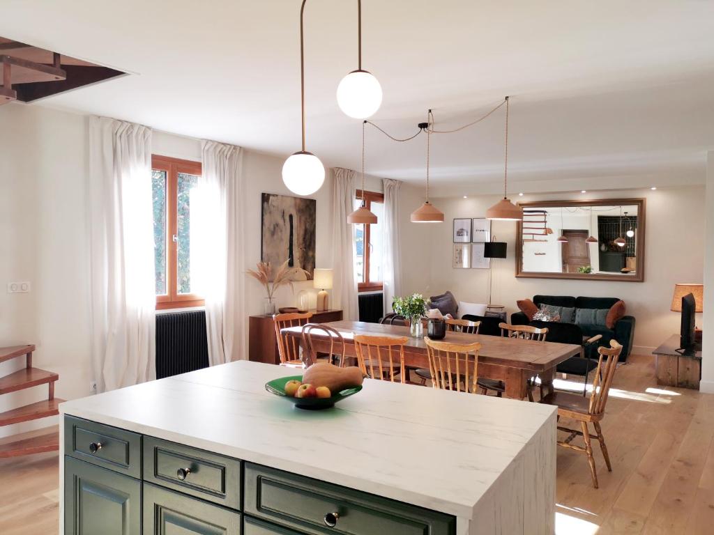 une cuisine et un salon avec une table et une salle à manger dans l'établissement La Diligence, gîte de caractère au cœur d'Arbois, à Arbois
