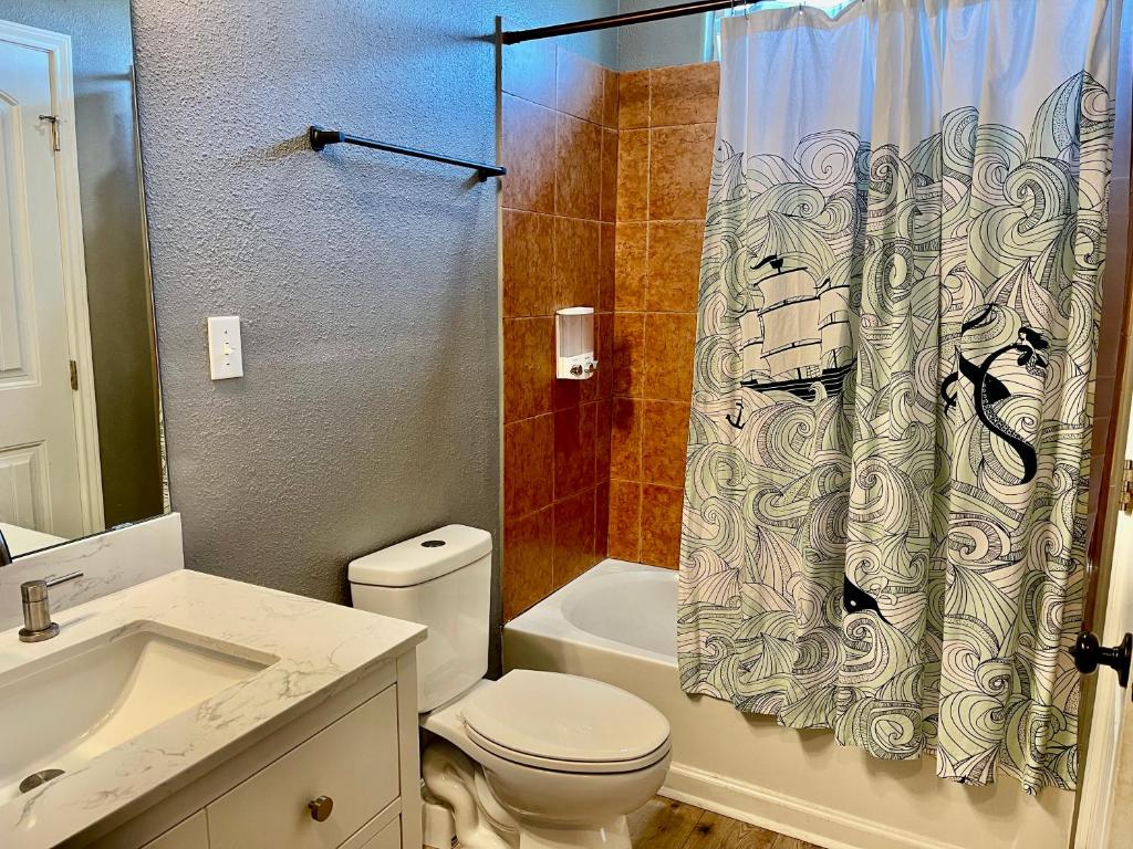 une salle de bain avec toilettes et rideau de douche dans l'établissement Stunning Beachfront 3 Bedroom Home, CoralMoonBeach, à Bolivar Peninsula