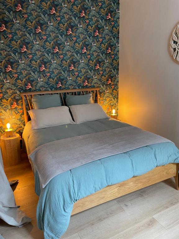 - une chambre avec un grand lit et du papier peint floral dans l'établissement Appartement Le Fayot, à Wimereux