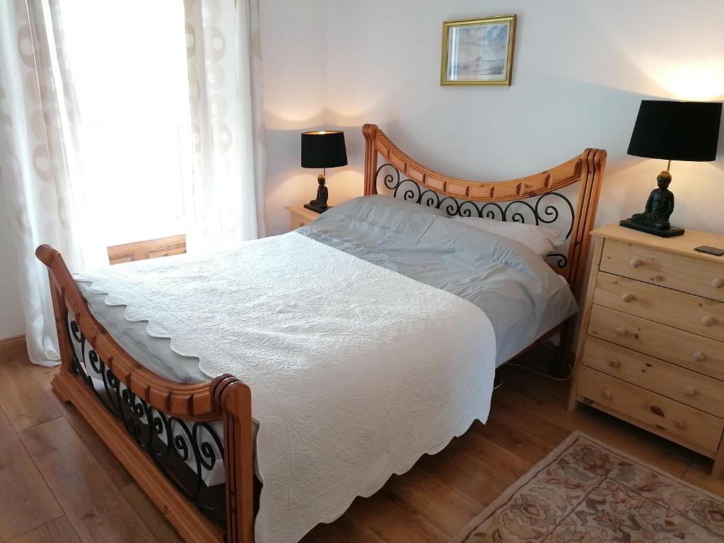 Dunkineely的住宿－Ferguson's Traditional Townhouse，一间卧室配有一张床和一个带两盏灯的梳妆台。