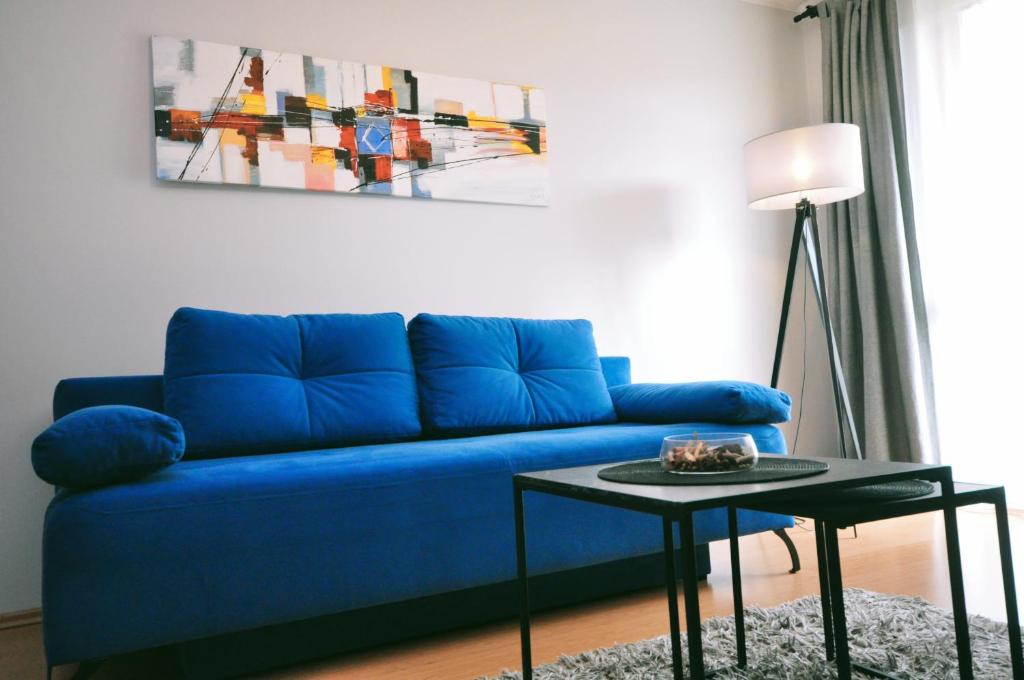 a blue couch in a living room with a table at Aquapark with private garage by JoApart in Kraków