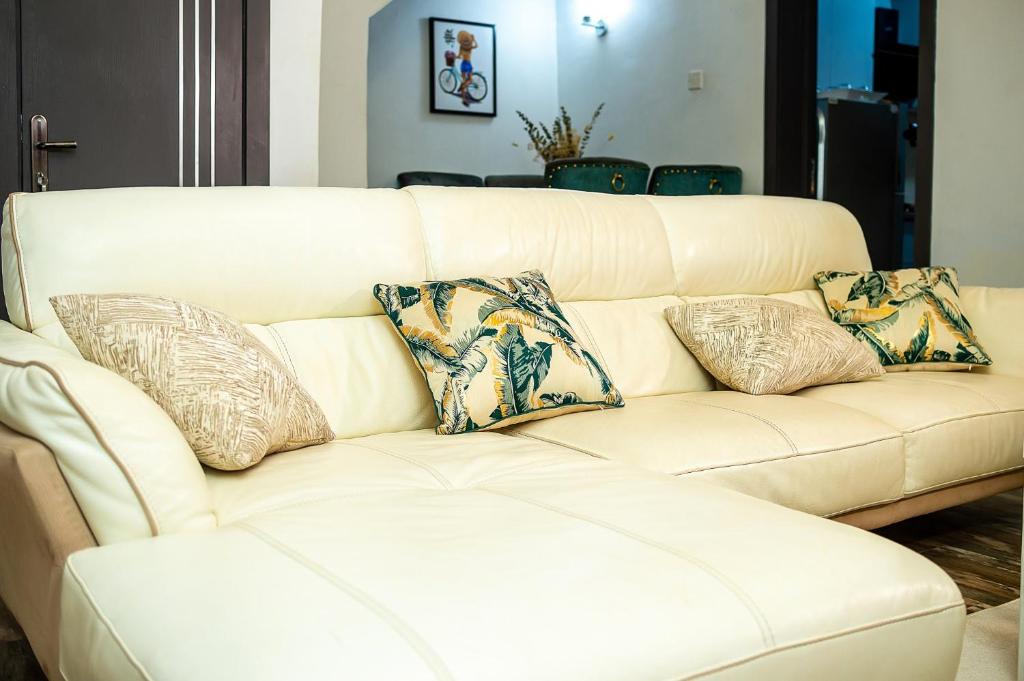 Un sofá blanco con cuatro almohadas. en Palm Heights Apartments - Omole Phase 1, Ikeja en Ikeja