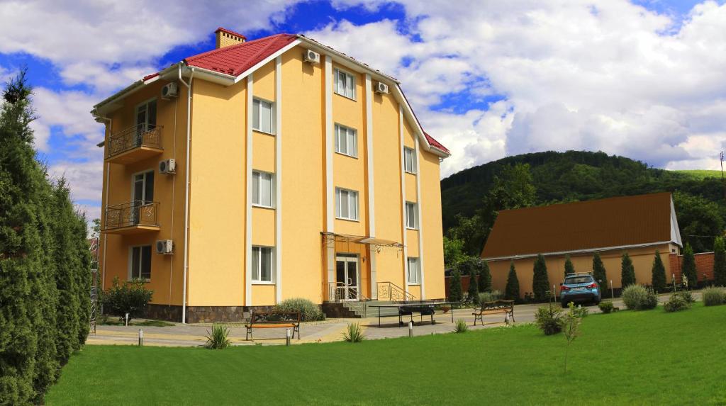 duży żółty budynek z ławką przed nim w obiekcie Zakarpatskiy Oazis w mieście Karpaty