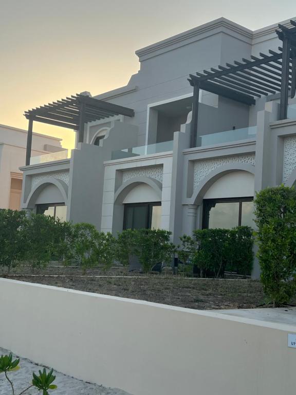 a white house with a fence in front of it at Cozy new townhouse for 6 people! in Salalah
