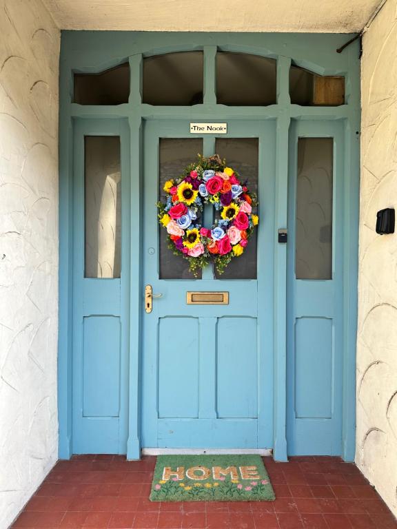 a blue door with a wreath on it at Clare's Cottage Near Cartmel - Dog Friendly, Homely, Aga, Log Burners, Disney Plus & Netflix in Holker