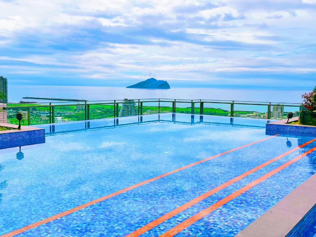 a swimming pool on top of a building overlooking the ocean at 光嶼海溫泉海景無邊際泳池豪華套房 in Hsin-hsing