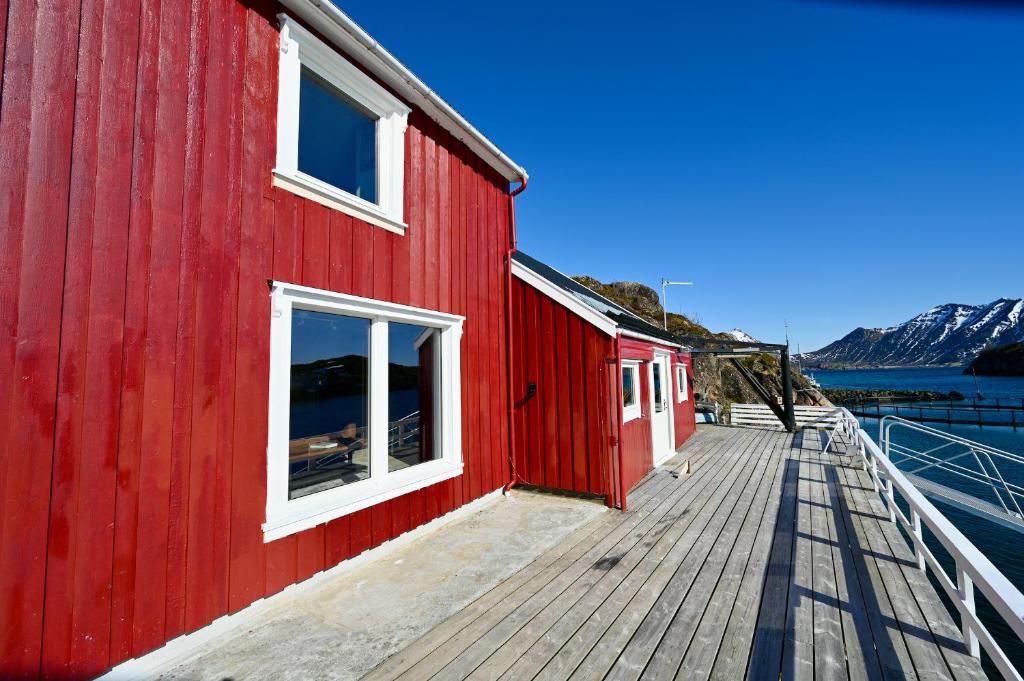 a red building on a dock next to a body of water at Fishermans Dock Lofoten in Ballstad