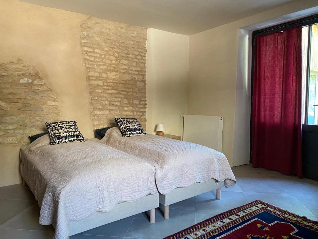 a bedroom with two beds and a brick wall at Moulin de la Rouchotte in Frétigney-et-Velloreille