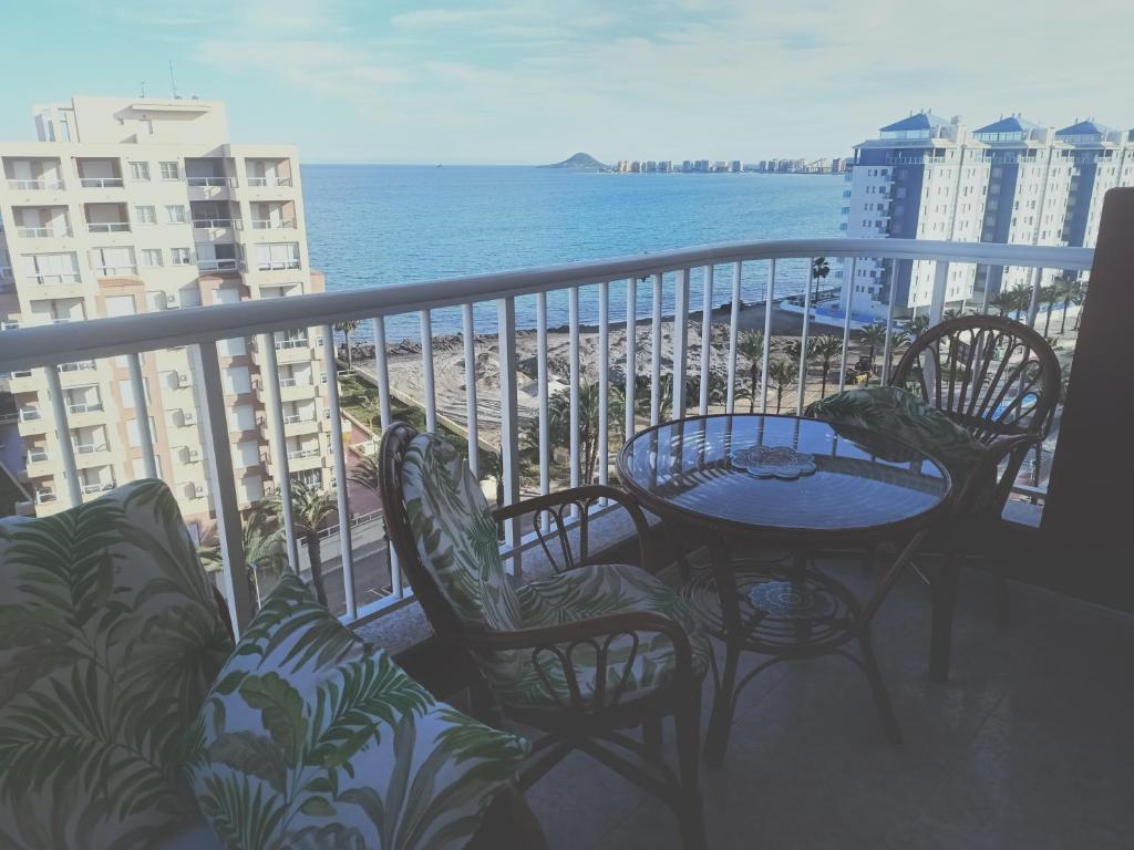 einen Balkon mit einem Tisch, Stühlen und Meerblick in der Unterkunft Apartamento Las Gondolas-Tiziano in La Manga del Mar Menor