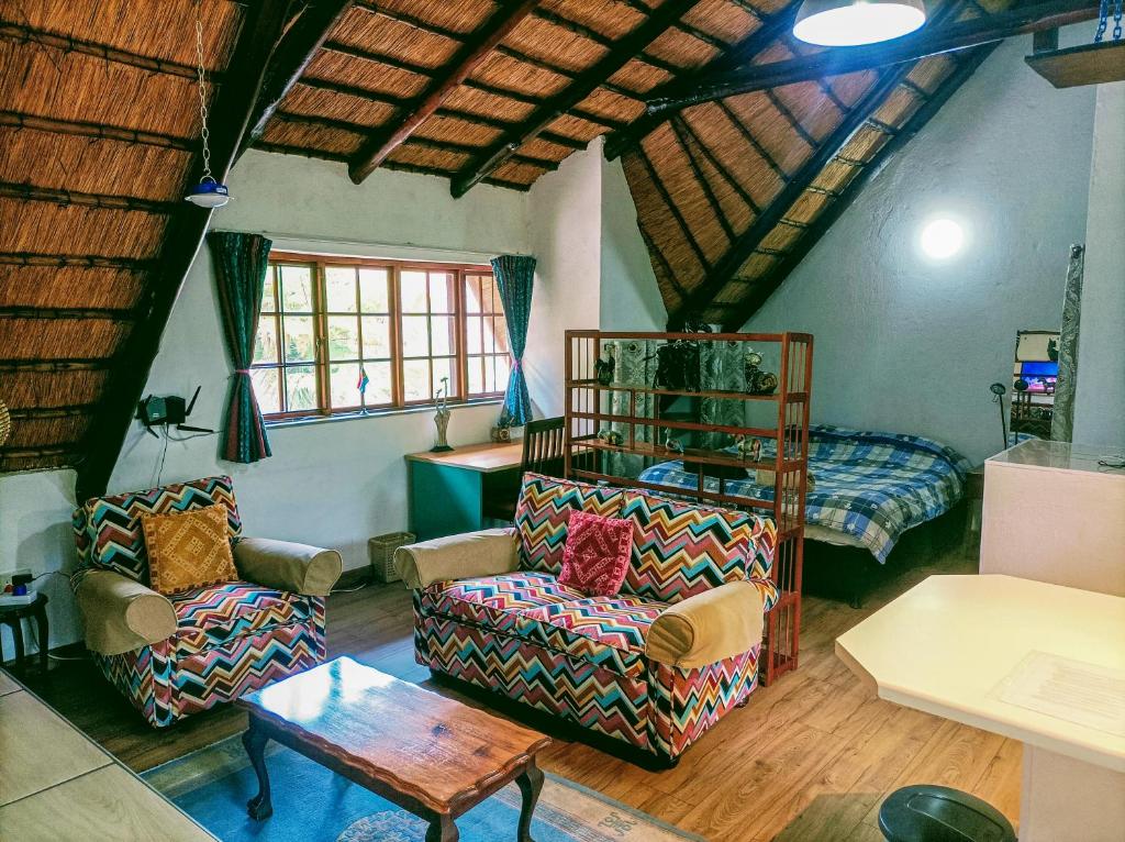 een woonkamer met 2 stoelen en een bed bij Creekside in the City in Johannesburg