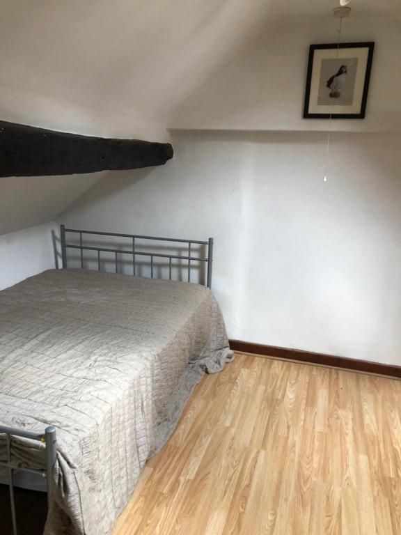 1 dormitorio con 1 cama y suelo de madera en The Coach House Cottage, Bridge House Mews en Newbold