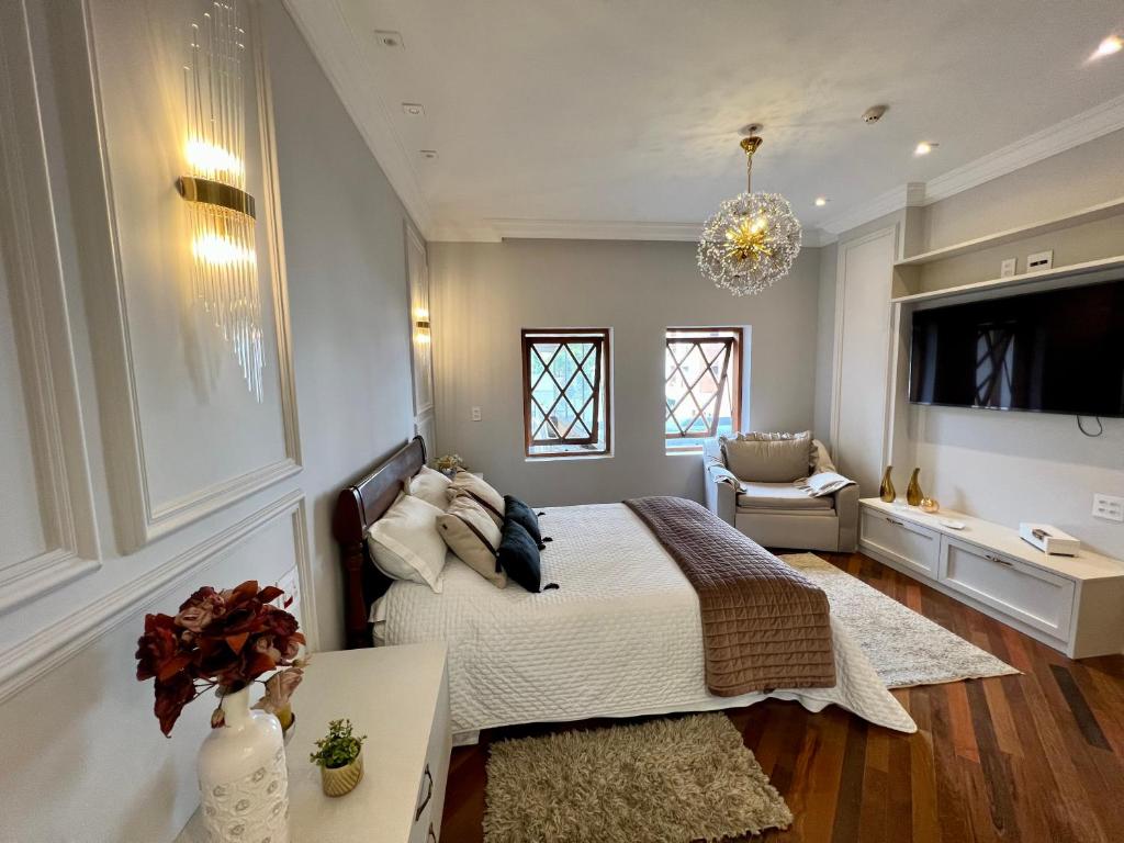 1 dormitorio con cama, sofá y TV en Flat Excepcional no Centro de Capivari en Campos do Jordão