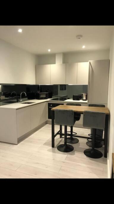 a kitchen with white cabinets and a table in it at Central Camberley Apartment - Parking - Garden in Camberley