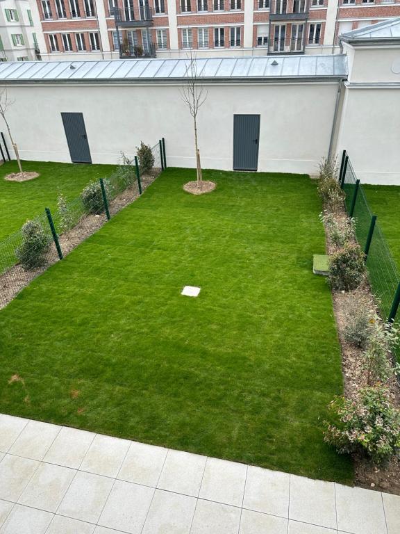 un patio con césped verde y un edificio en Disneyland Paris, vallée village ,Paris , villa, garden , Syline Home, 120 m2 en Serris