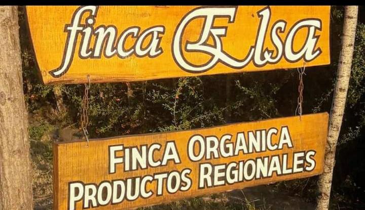 two signs hanging from a wooden pole with a sign for a store at Finca ELSA in San Agustín de Valle Fértil
